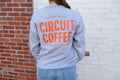 Person wearing a gray sweatshirt with 'Circuit Coffee' text against a brick wall.